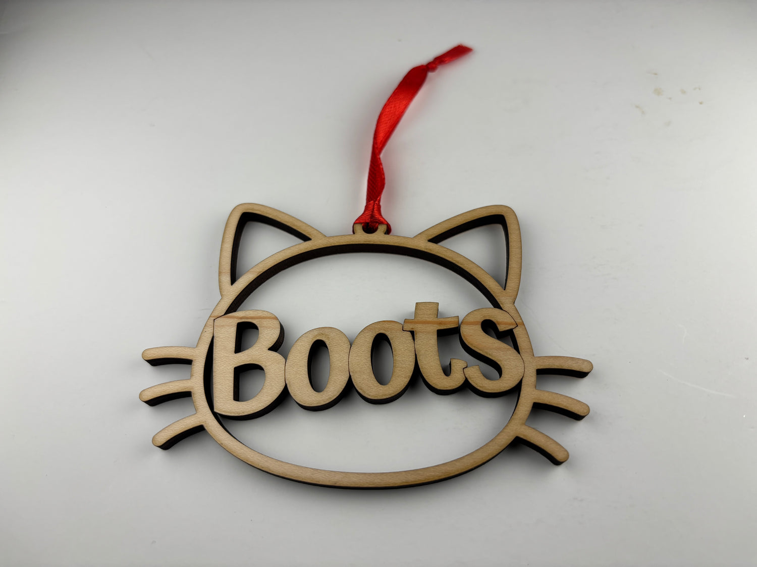 Wooden ornament shaped like a cat with 'Boots' text on a white background