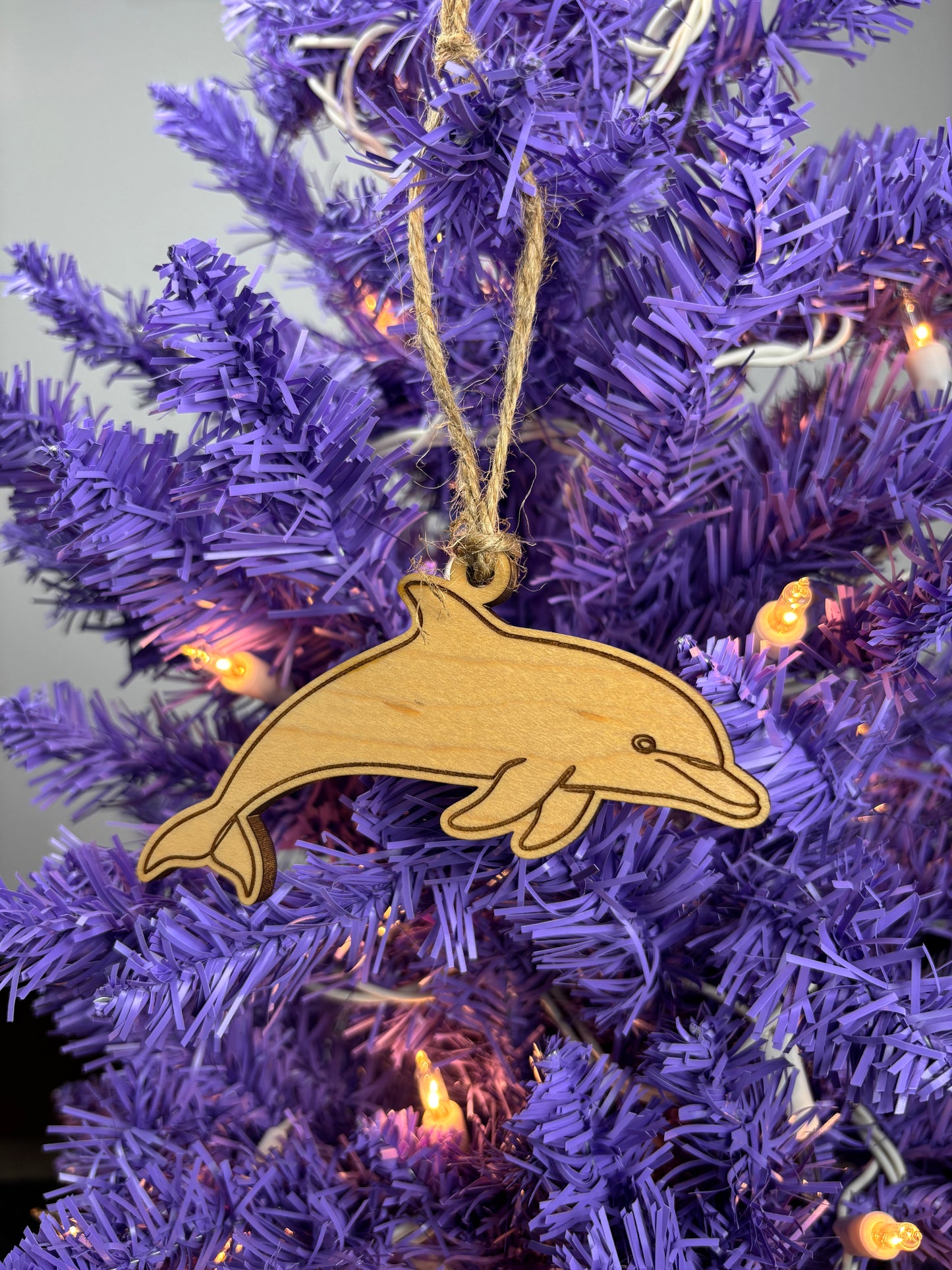 Wooden dolphin ornament on a purple Christmas tree with lights