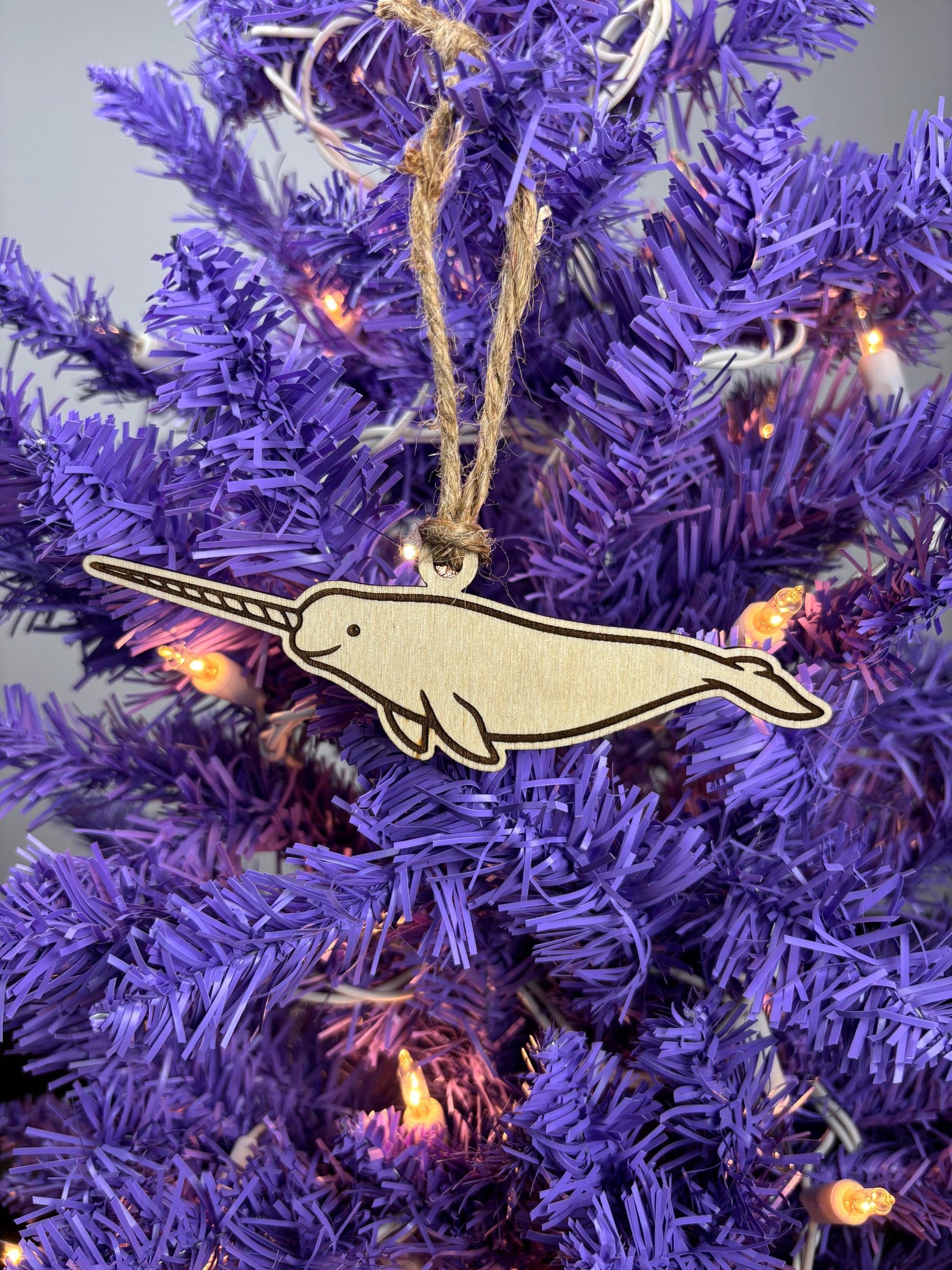 Narwhal ornament on a purple Christmas tree with lights