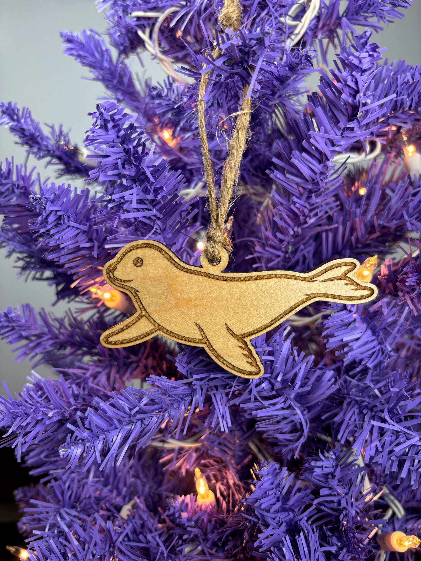 Wooden seal ornament on a purple Christmas tree with lights.