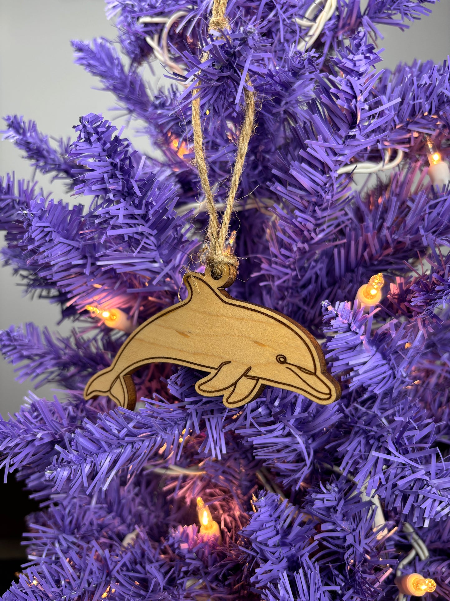 Wooden dolphin ornament on a purple Christmas tree with lights
