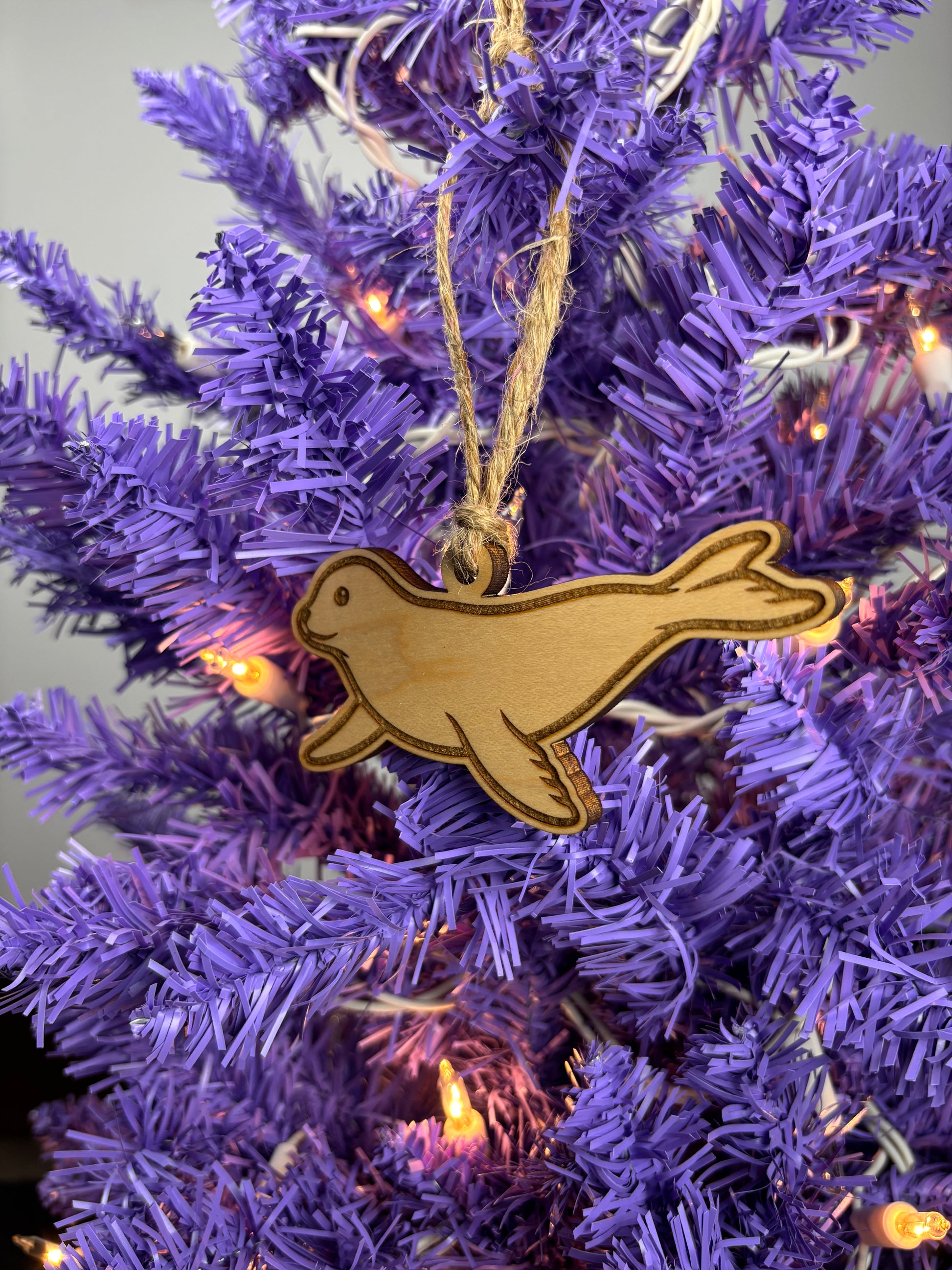 Wooden seal ornament on a purple Christmas tree with lights.